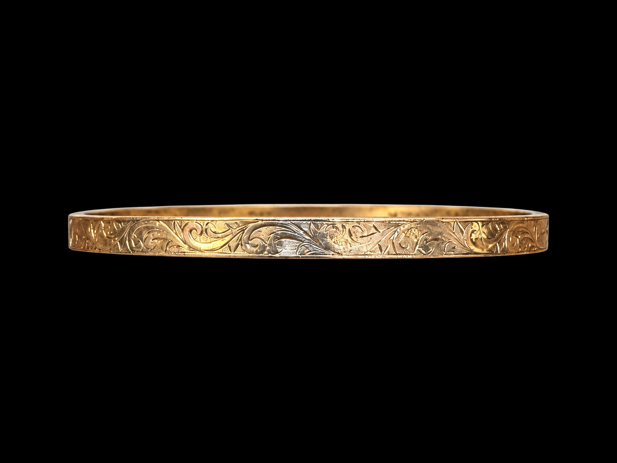 EARLY 20TH CENTURY SCROLL 9 KARAT GOLD CASED BANGLE on black background