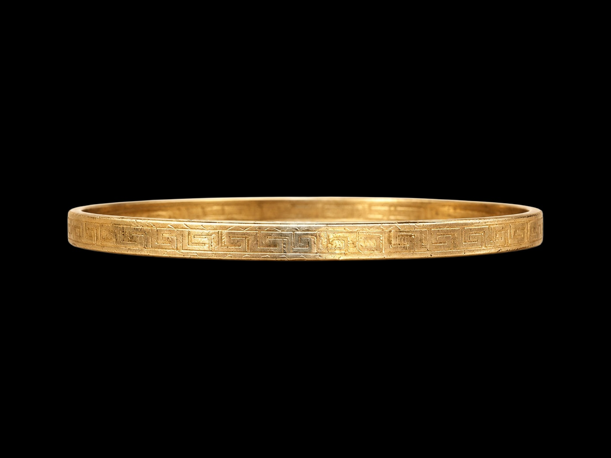 EARLY 20TH CENTURY GREEK KEY 9 KARAT GOLD CASED BANGLE on black background