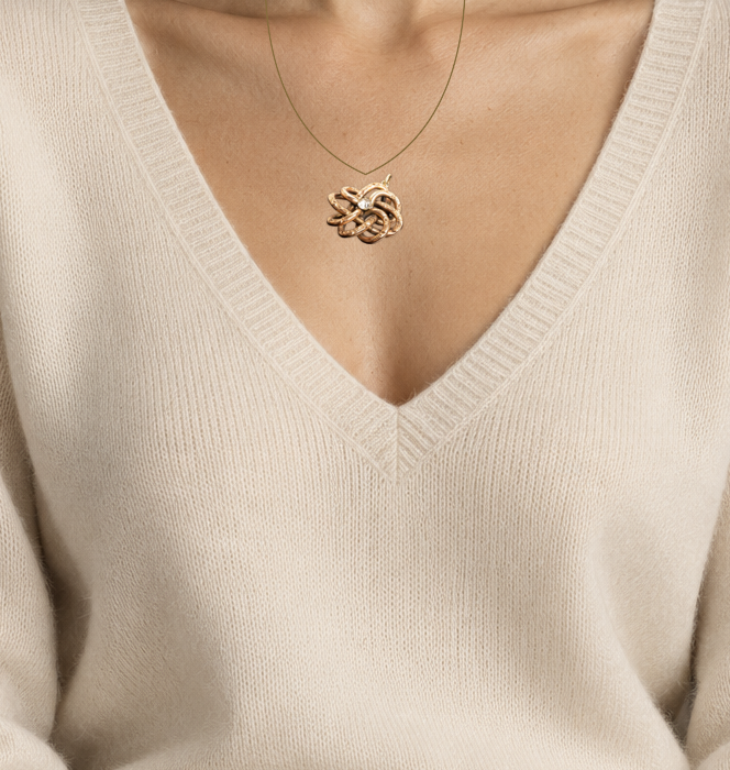 Illustrative close wearing detail of victorian gold filled lovers knot paste pendant with 14k gold bail. Original photographed jewelry preserved; scale approximate.