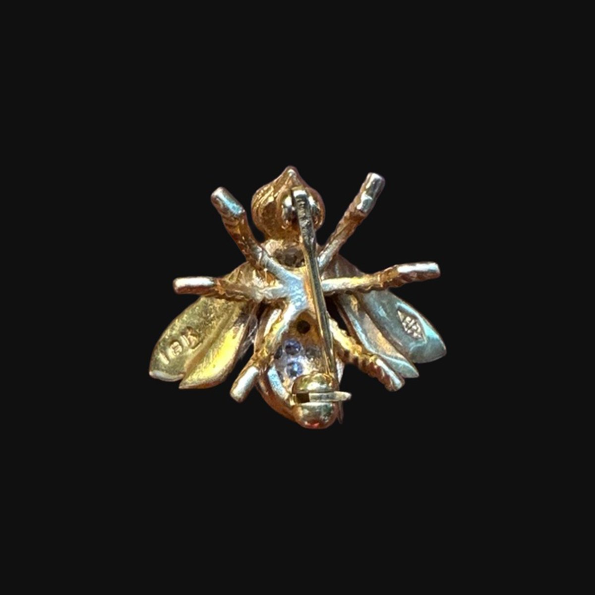 Reverse of 18k gold bee brooch on black background with original hallmarks preserved