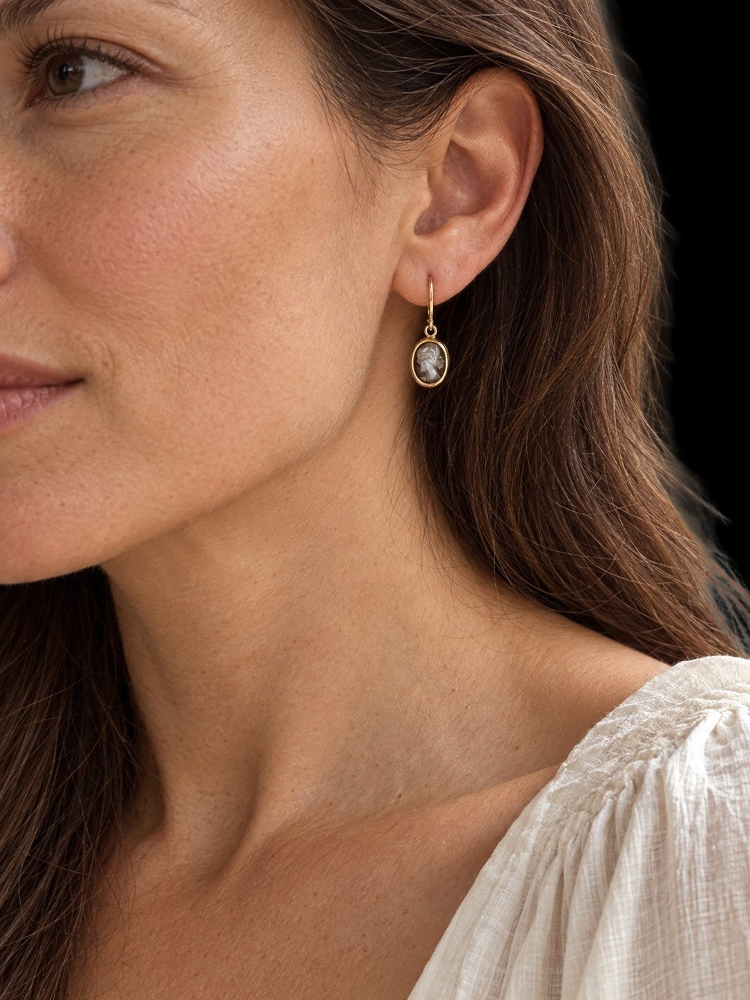 Model wearing EARLY 20TH CENTURY MINIATURE CAMEO EARRINGS IN 14 KARAT GOLD against a black background