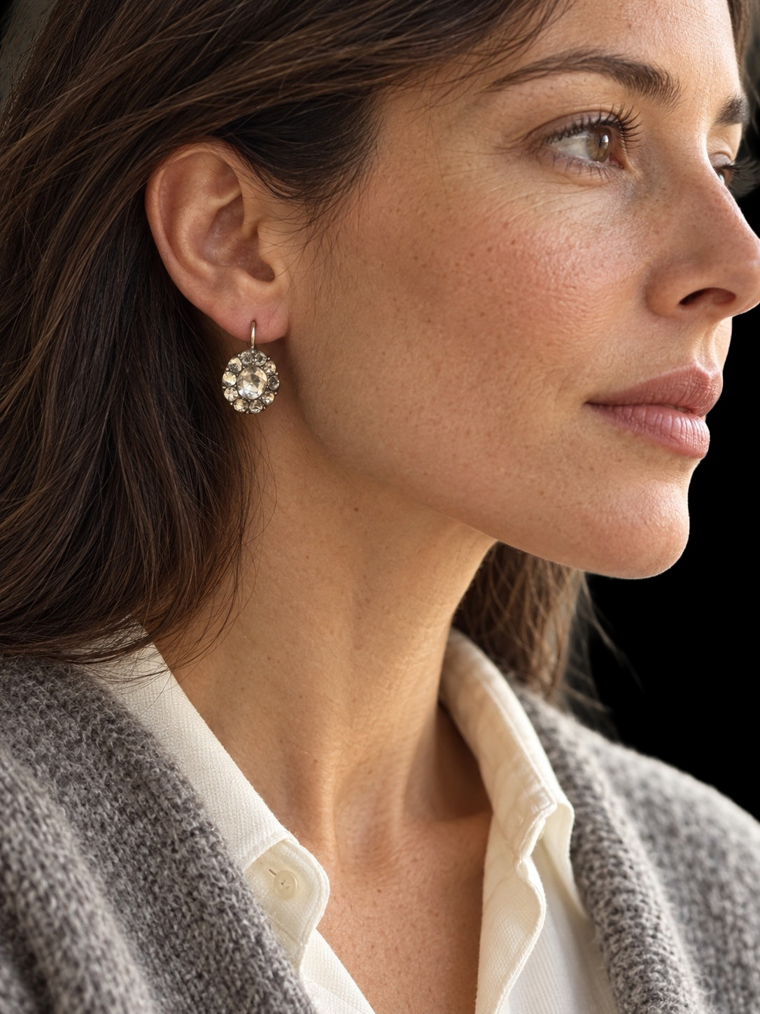Model wearing 18TH CENTURY GEORGIAN PASTE CLUSTER EARRINGS IN SILVER against a black background
