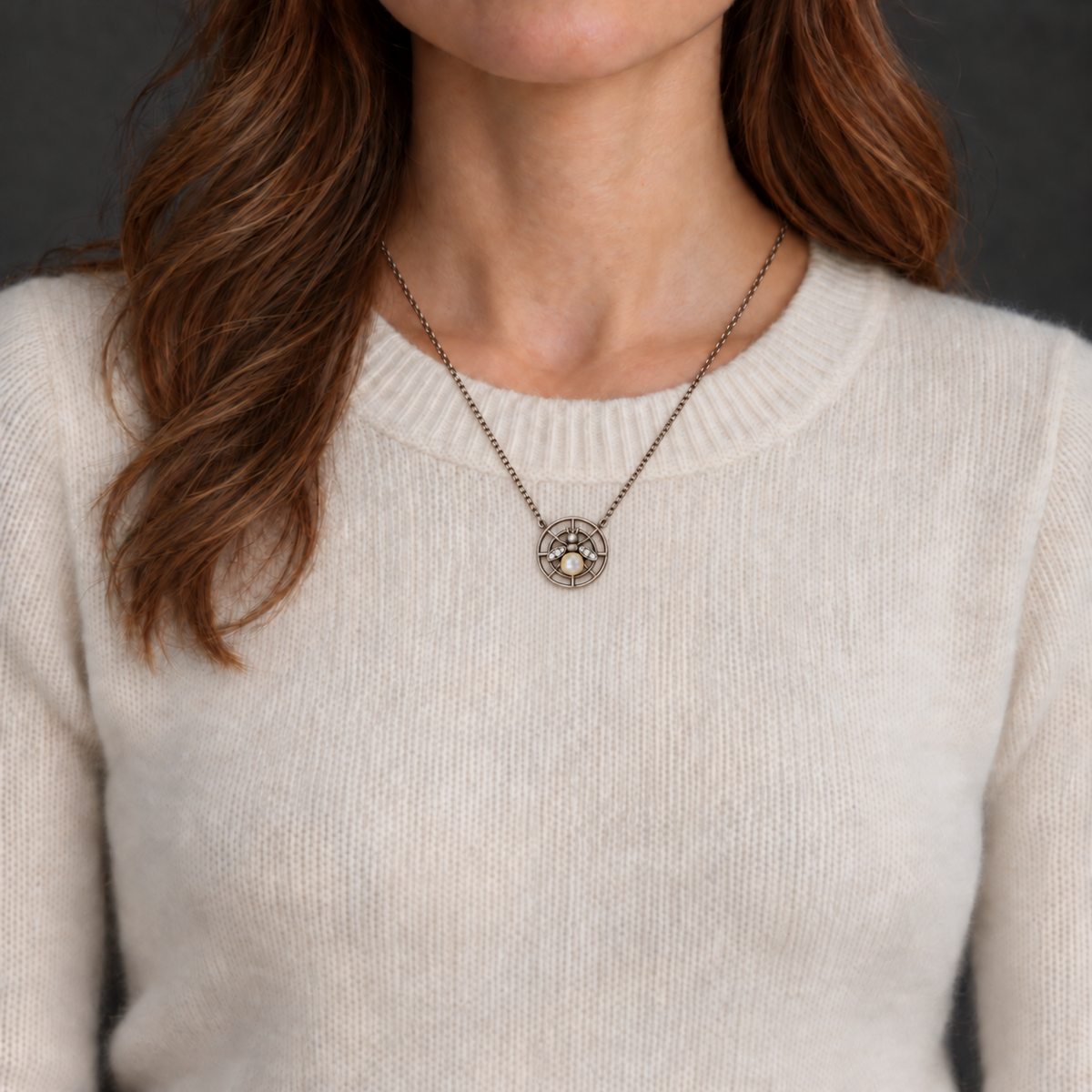 AI styling illustration of the bee necklace worn over ivory cashmere; pendant scale approximate