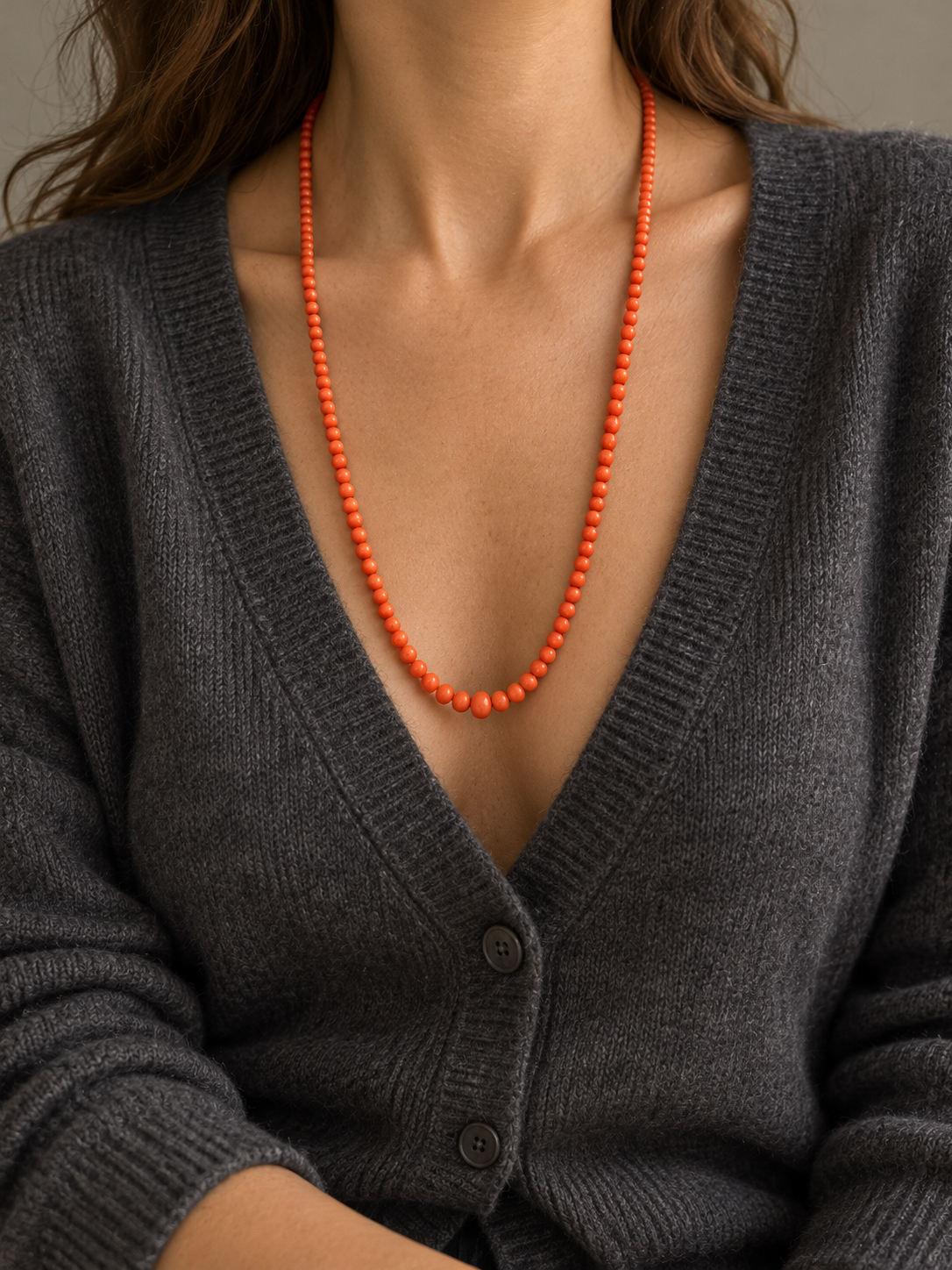 AI GENERATED STYLING ILLUSTRATION OF THE VICTORIAN NATURAL CORAL NECKLACE WORN WITH CASHMERE; SCALE APPROXIMATE