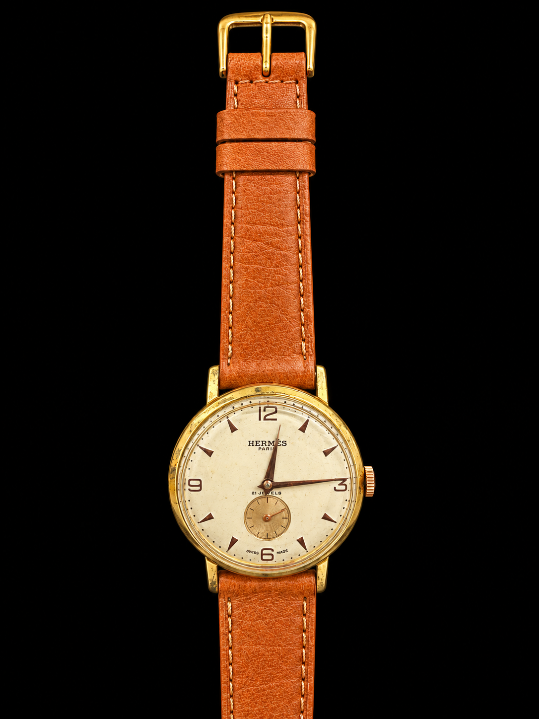 VINTAGE WATCH WITH HERMÈS SIGNED CREAM DIAL AND COGNAC STRAP ON BLACK BACKGROUND